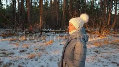 一个穿着羽绒服戴着白色帽子的女人在阳光明媚的日子在冬季公园散步，在新鲜的空气中散步